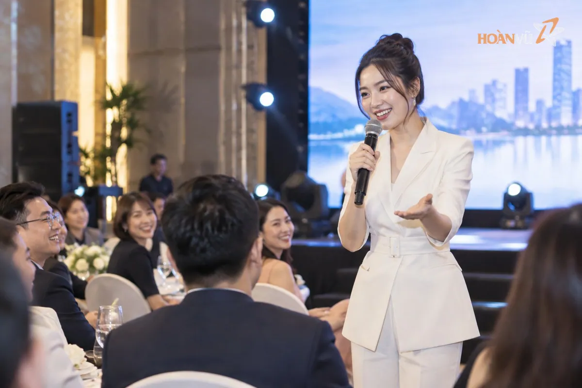 MC trẻ tự tin cầm micro mỉm cười giao lưu với khán giả trong hội trường sự kiện doanh