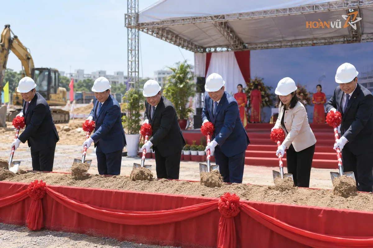 Các đại biểu đội mũ bảo hộ cầm xẻng xúc đất trong nghi thức động thổ tại công trường,